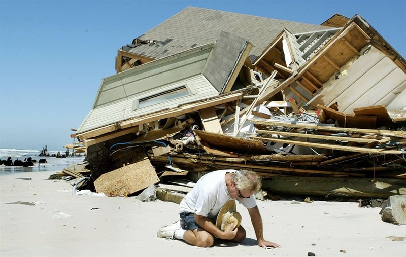 Владелец этого дома на Капе Сан Бласе, Флорида, молится после урагана Иван, разрушившего его дом и сотни подобных этому домов по всему побережью. Ущерб причиненный недвижимости в США достиг $15,5 миллиардов. Кроме того, Иван забрал 25 жизней в штатах Флорида и Алабама. (Phil Coale/AP)