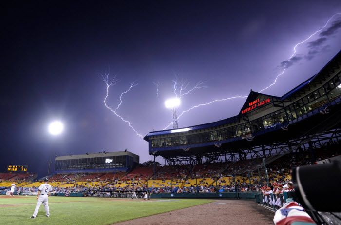 Вспышки молнии освещают небо над стадионом «Rosenblatt» на котором проходит бейсбольный матч в рамках соревнований «NCAA College World Series», Омаха, Небраска, 20 июня 2010 года. (AP Photo/Eric Francis)