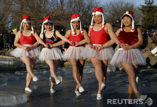 Шиньян, Китай. Девушки-Санта-Клаусы исполняют танец маленьких лебедей перед купанием в проруби
