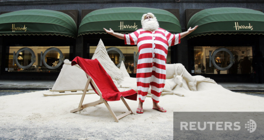 Артист в костюме Санта-Клауса позирует журналистам у входа в универмаг Harrods в Лондоне