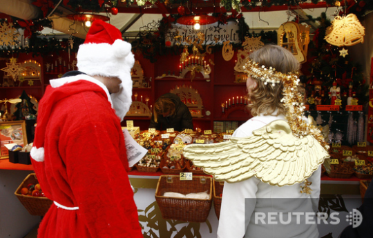 Санта и его помощница прицениваются к сладостям на рождественской ярмарке в Гамбурге, Германия